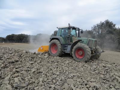 Tracteur avec broyeur de pierres en action dans la poussière